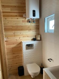 łazienka z toaletą i drewnianą ścianą w obiekcie Domki Kalimera Rewal w Rewalu