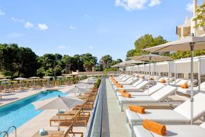 einen Pool mit Liegestühlen und Sonnenschirmen in einem Resort in der Unterkunft VIVA Cala Mesquida Suites & Spa Adults Only 16 in Cala Mesquida