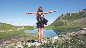 Una donna in piedi sulla cima di una montagna con le braccia tese di Hôtel Alexane a Samoëns