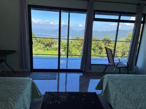 モンテベルデ・コスタリカにあるVistaverde Lodgeのベッド2台と大きな窓が備わる客室です。