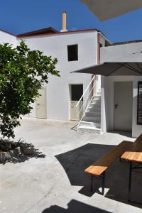 a white building with a bench and an umbrella at Casa vacanze Pabaule in Gonnesa