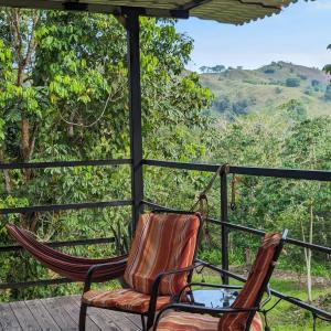 two chairs on a porch with a view of the mountains at Rainforest Lodge del Rio in Portobelo
