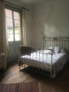 una camera con un letto in una stanza con una finestra di Les anciens thermes a Soultzbach-les-Bains