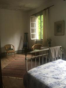 a bedroom with a bed and two chairs and a window at Les anciens thermes in Soultzbach-les-Bains