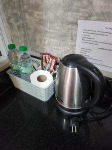 Loft House Resort Pattaya في جومتين بيتش: وعاء الشاي وورق التواليت وزجاجات المياه على منضدة