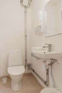 a white bathroom with a toilet and a sink at Vallersviks Vandrarhem Änggården in Frillesås