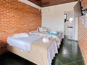 Pousada Maravista في كانانيا: سريرين في غرفة مع جدار من الطوب