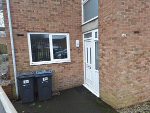 two trash cans next to a brick building with a door at Birmingham City Homestay in Birmingham