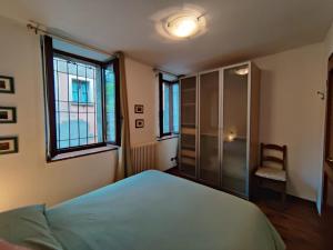 a bedroom with a bed and a chair and two windows at Casa Relax in Bellano