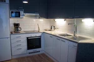 kuchnia z białymi szafkami i zlewem w obiekcie Aurinkolahti cosy apartment with warm parking w Helsinkach