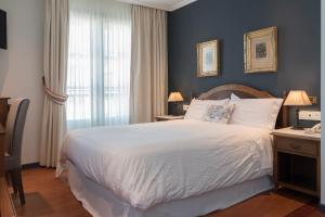 Un dormitorio con una gran cama blanca y una ventana en Hotel Monumento Convento de San Benito, en A Guarda