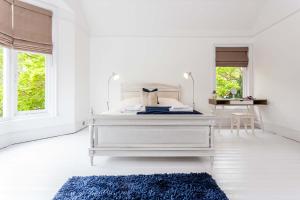 a white bedroom with a white bed and a blue rug at Guest Homes - The Grove in Hartlepool