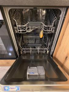 an open dishwasher with a cell phone in it at Apartment Unamare in Belgrade