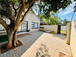 a house with a tree and a brick driveway at Ivanka's Self-Catering Flat in Kimberley