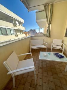 a balcony with two white chairs and a table at Civico 54 in Alghero