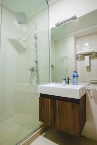 ein Bad mit einem Waschbecken und einer Dusche mit einem Spiegel in der Unterkunft BON Hotel Imperial in Abuja