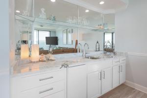Una cocina blanca con fregadero y espejo. en Phoenix on the Bay 1506 condo, en Orange Beach