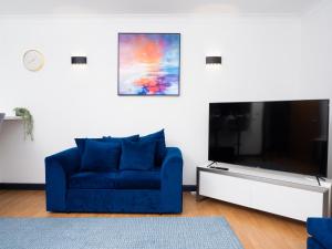 um sofá azul numa sala de estar com uma televisão grande em Ramsgate Boutique Apartment em Ramsgate