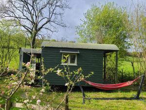 a green house with a hammock in front of it at Penn Bergeyn Shepherd's Huts in Exeter