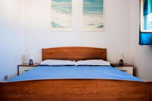 a bedroom with a wooden bed with a blue blanket at Attico De Gasperi in Orosei