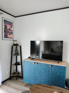 un salon avec une télévision sur une commode bleue dans l'établissement Cottage du Lac, à Olonzac