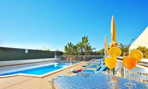 Villa Honolulu by Algarve Vacation في ألبوفيرا: مسبح عليه كراسي وطاولة عليها شرائح برتقال