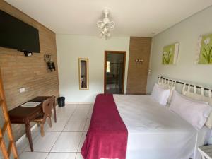 a bedroom with a large white bed and a desk at Villa Cottage Pousada in Monte Alegre do Sul