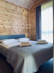 um quarto com uma cama grande e uma parede de madeira em NB Houses Šventoji em Šventoji