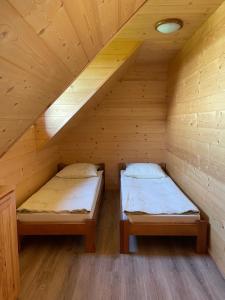 two beds in a wooden attic room at Domki Za Górą in Jazowsko