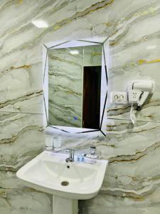 La salle de bains est pourvue d'un lavabo et d'un miroir sur un mur en pierre. dans l'établissement SHUKRONA Hotel, à Samarcande