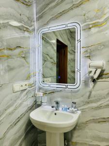 ein Bad mit einem Waschbecken und einem Spiegel in der Unterkunft SHUKRONA Hotel in Samarkand
