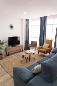ein Wohnzimmer mit einem blauen Sofa und einem TV in der Unterkunft Calvario 53 by 7Escalones in Rota