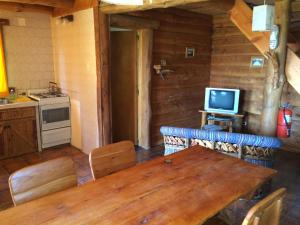 a kitchen with a wooden table and a television at Cabañas La Pampita in Villa La Angostura