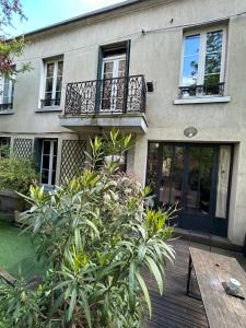 een huis met een houten terras met een houten tafel bij Maison stylée avec jardin caché, Vincennes in Vincennes