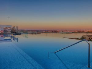 une grande piscine avec vue sur la rivière dans l'établissement Jupiter Marina Hotel - Couples & Spa, à Portimão