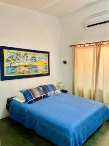 Hotel The Winds Of Margarita في El Yaque: غرفة نوم بسرير ازرق مع لوحة على الحائط