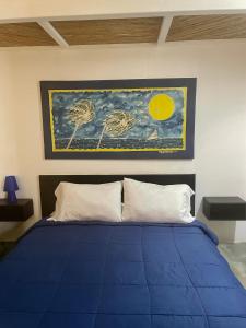 um quarto com uma cama azul com um quadro na parede em Hotel The Winds Of Margarita em El Yaque
