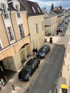 two cars parked on a street next to buildings at Appartement centre ville in Fontainebleau
