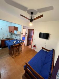 uma sala de estar com uma mesa azul e uma cozinha em Apê Itaguá - CentrinhoTurístico de Ubatuba em Ubatuba