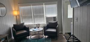 uma sala de estar com duas cadeiras, uma mesa e uma janela em Saltaire Cottages em Kitty Hawk Beach