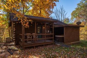 a small cabin in the woods with a deck at Blue Rose Cabins - Lincoln Log Cabin in Logan