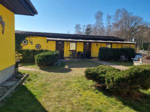 una casa amarilla con un patio delante en Pension Wiesenperle en Trassenheide
