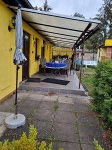 une terrasse avec une table bleue et un parasol dans l'établissement Pension Wiesenperle, à Trassenheide