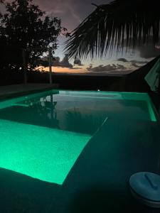 una piscina con luz verde frente a la puesta de sol en Casa vista al mar y las montañas río san Juan a solo 4 minutos de centro del pueblo y las playas en Río San Juan