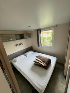 ein kleines Schlafzimmer mit einem Bett mit einer Decke darauf in der Unterkunft Mobil-home bord de mer in Vendres + 7 Fotos