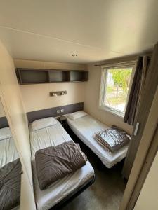 2 camas en una habitación pequeña con ventana en Mobil-home bord de mer, en Vendres
