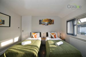 ティルベリーにある3 Bedroom Blissful Living for Contractors and Families Choice by Coraxe Short Staysの緑の毛布が備わる小さな部屋のベッド2台
