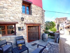 - un bâtiment en pierre avec une porte et des chaises en bois dans l'établissement Casasdetrevijano Cañon del rio leza, à Soto en Cameros