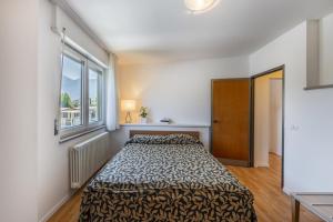 a bedroom with a bed in a room with a window at Riviera Beach House in Calceranica al Lago