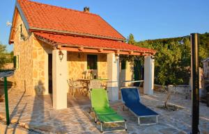 ein Haus mit einem orangenen Dach mit Stühlen und einem Tisch in der Unterkunft STONE HOUSE ANA in Škrip